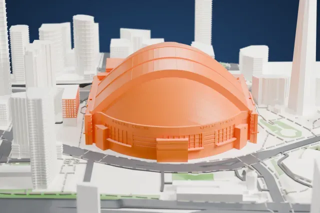 A white 3D print of Rogers Centre, a domed stadium with a ribbed curved roof, with a tall slender tower, tall buildings and roads around it.