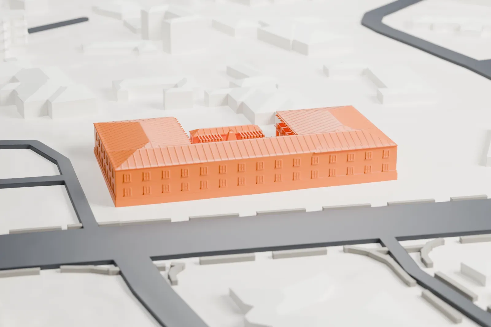 A white 3D print of the Royal Palms, a two-story U-shaped building with ribbed hip roofs around a courtyard, beside a wide road with houses nearby.