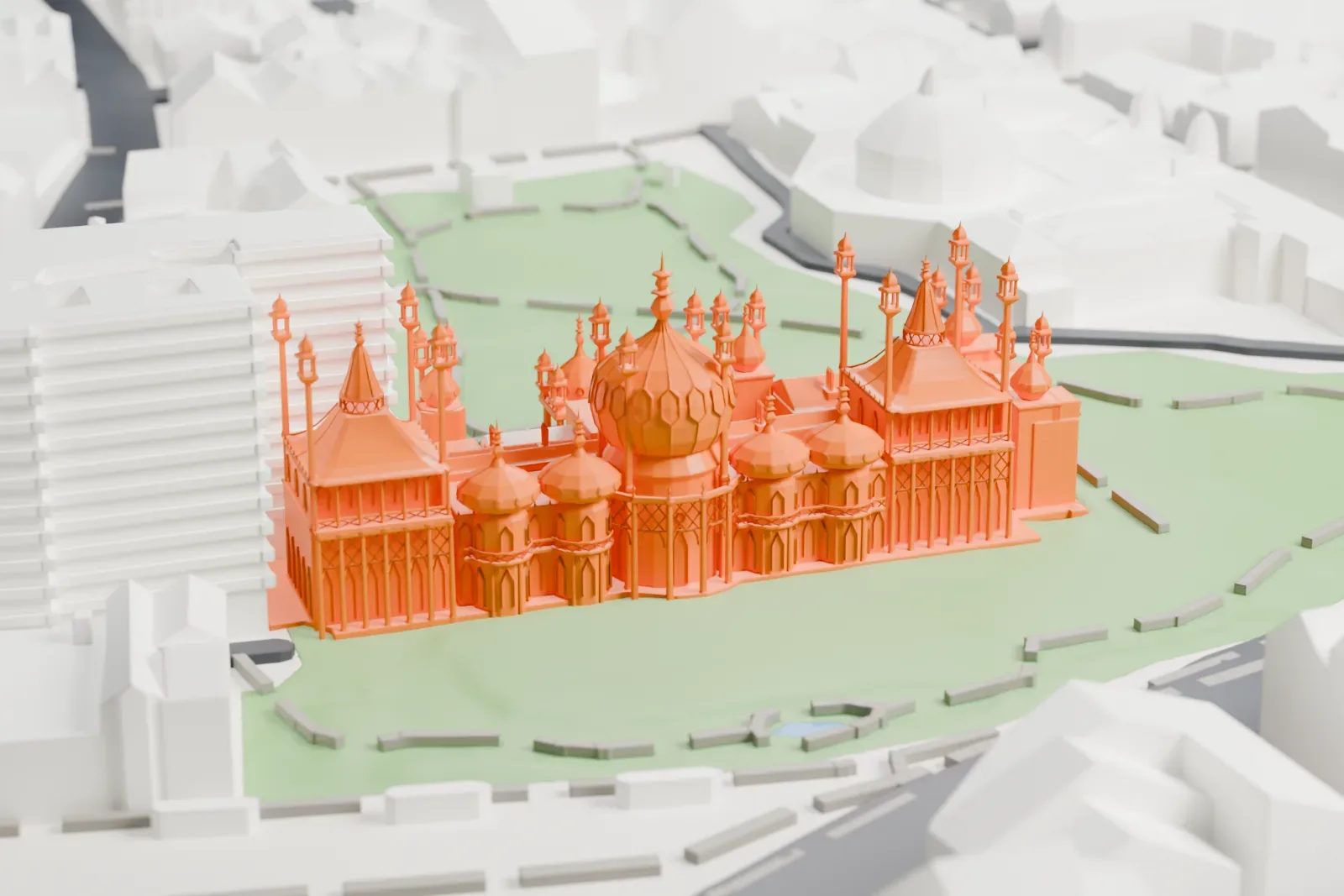 A white 3D print of the Royal Pavilion, a building with a large central dome and many slender minarets, set in green gardens with streets and buildings around it.