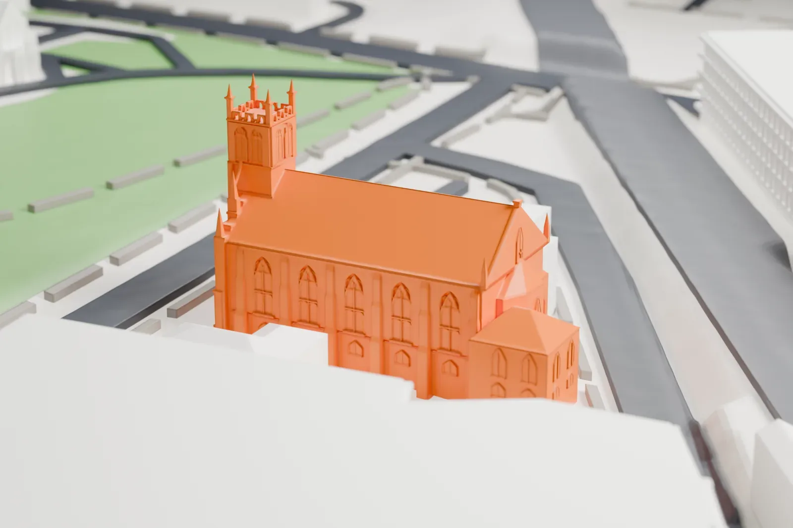 A white 3D print of Saint Peter the Apostle Church, a Gothic-style church with a tall square tower and a long steep roof, beside streets, a green park and larger buildings.