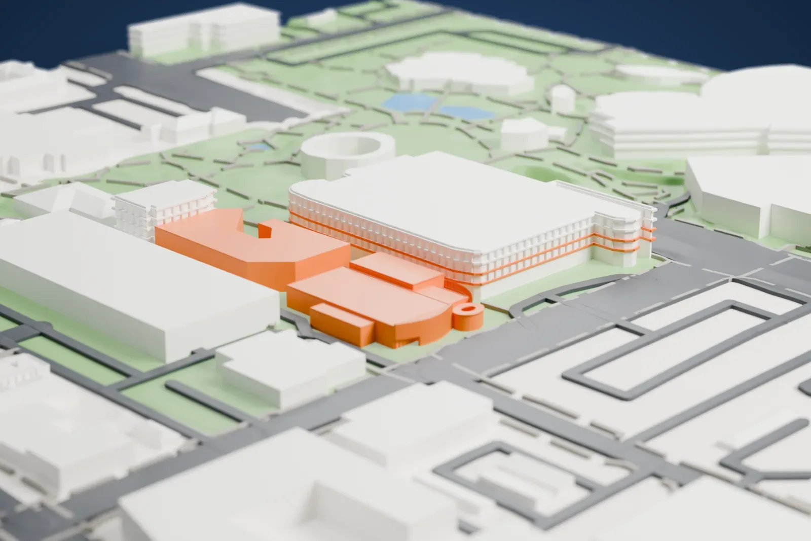 A white 3D print of the Scottsdale Museum of Contemporary Art, a low building with a curved front and a round drum with an open top, among streets and green ground.