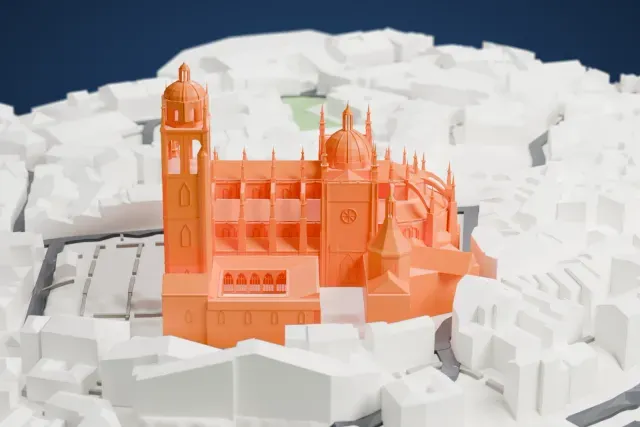 A white 3D print of Segovia Cathedral, with its tall tower and many pinnacles, surrounded by closely packed buildings and narrow streets.