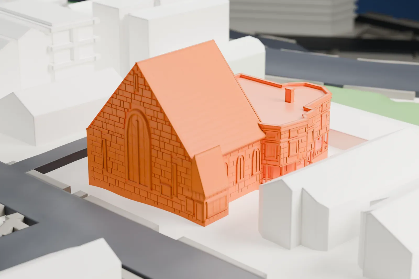 A white 3D print of Shri Swaminarayan Mandir, a stone-faced building with a tall gable and a bay-windowed wing, on a street corner among houses.