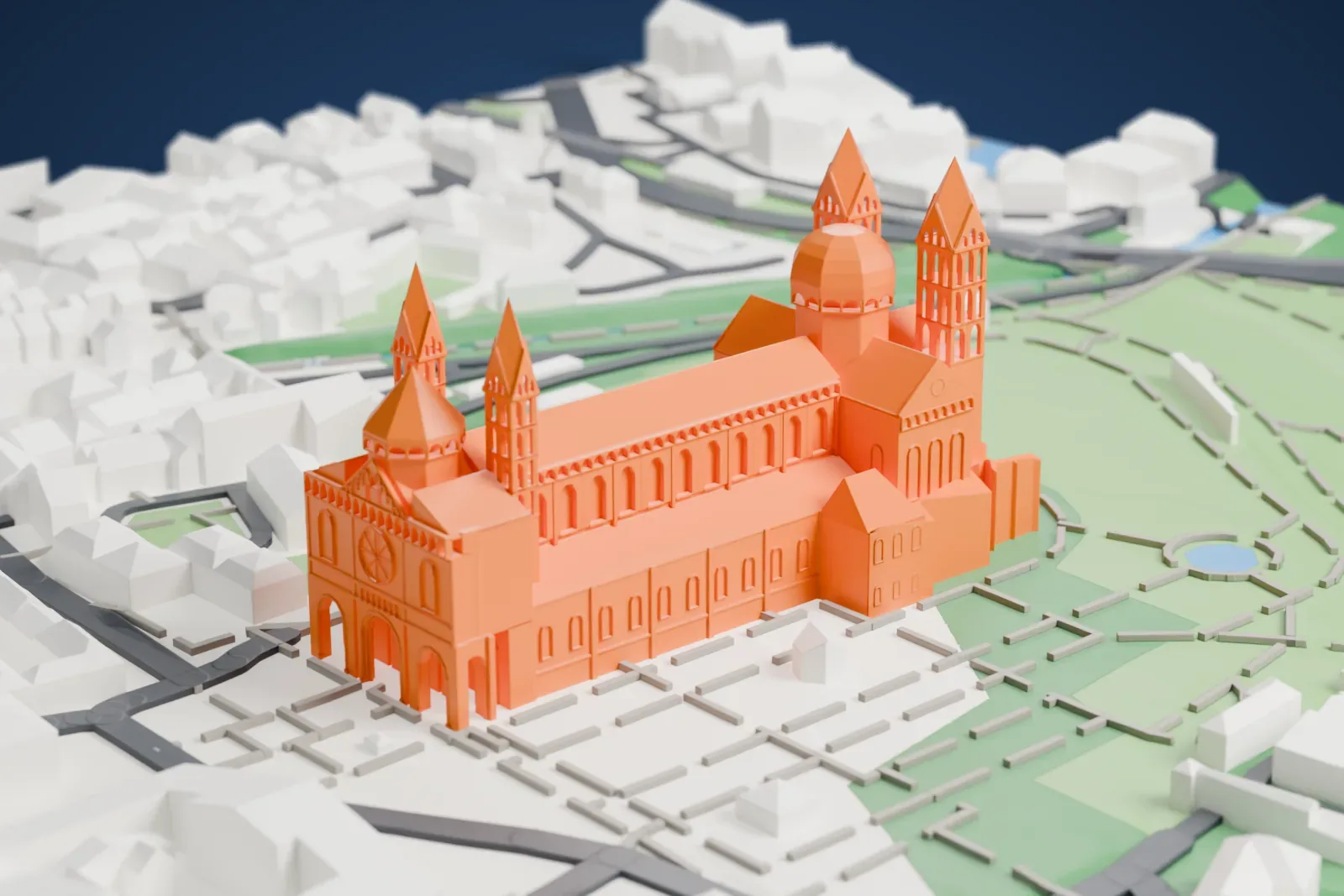 A white 3D print of Speyer Cathedral, a long church with four slender pointed towers, a domed crossing tower and a rounded east end, standing on green lawns with paths, small ponds and houses around it.