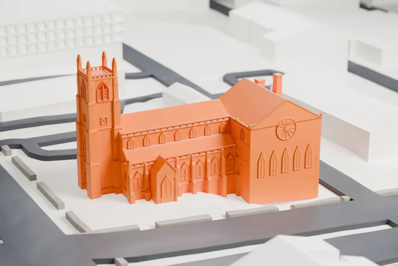 A white 3D print of St. James’ A.M.E. Church, a church with a tall front tower and a long nave, on its block between streets and low buildings.