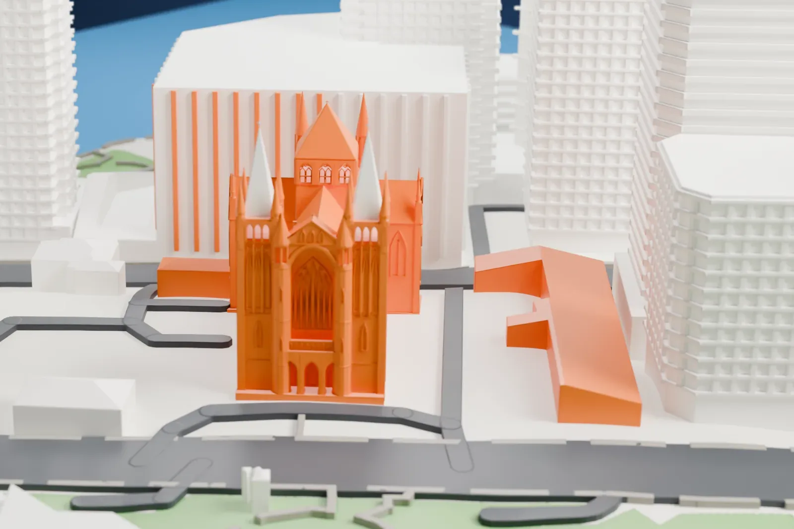 A white 3D print of St John's Cathedral, a Gothic Revival church with pointed spires and a central tower, hemmed in by tall city buildings, with a small park nearby.