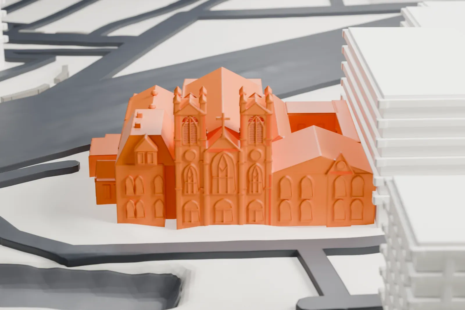 A white 3D print of St. John's Church, with twin pinnacled towers on its front, beside a street and large neighboring buildings.