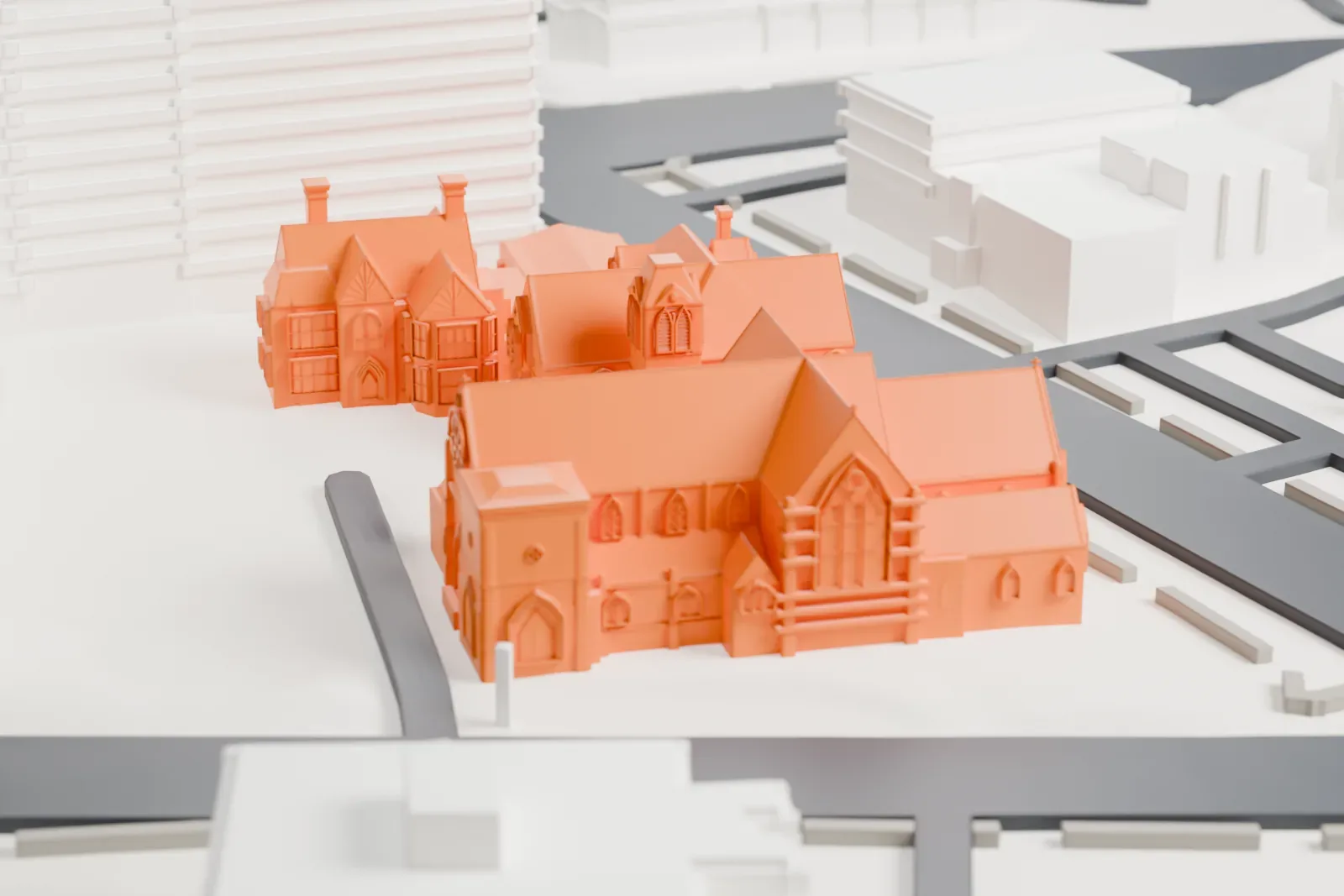 A white 3D print of St. John's Protestant Episcopal Church, a cluster of steep gabled roofs on a city block with taller buildings and streets around it.