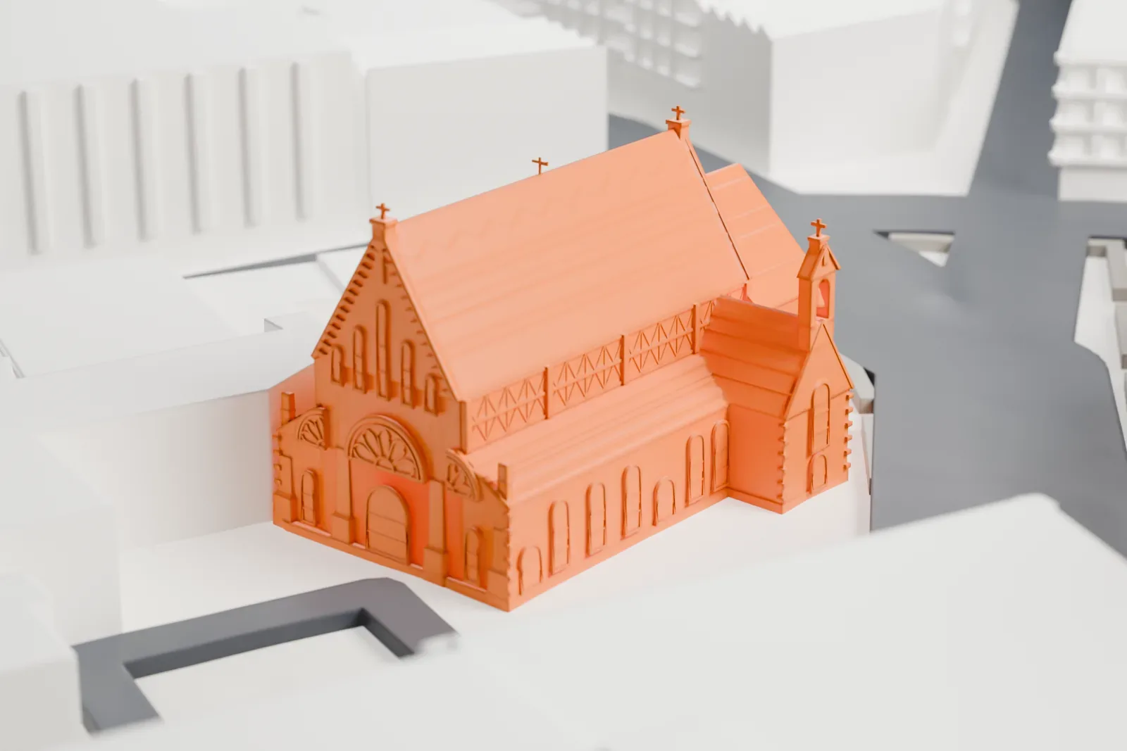 A white 3D print of St. John's Church in Yonkers, a cross-shaped church with steep roofs and small crosses on its gables, among taller buildings and streets.