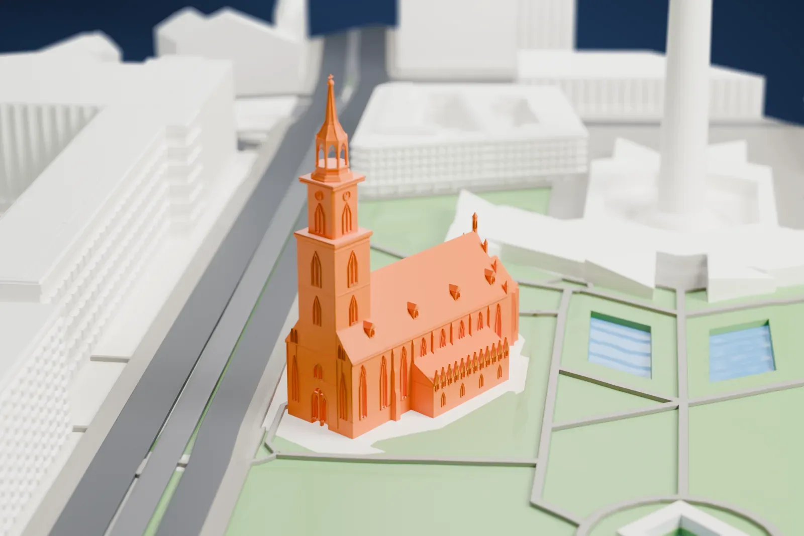 A white 3D print of St. Mary's Church in Berlin, a church with a tower among the surrounding streets and buildings.