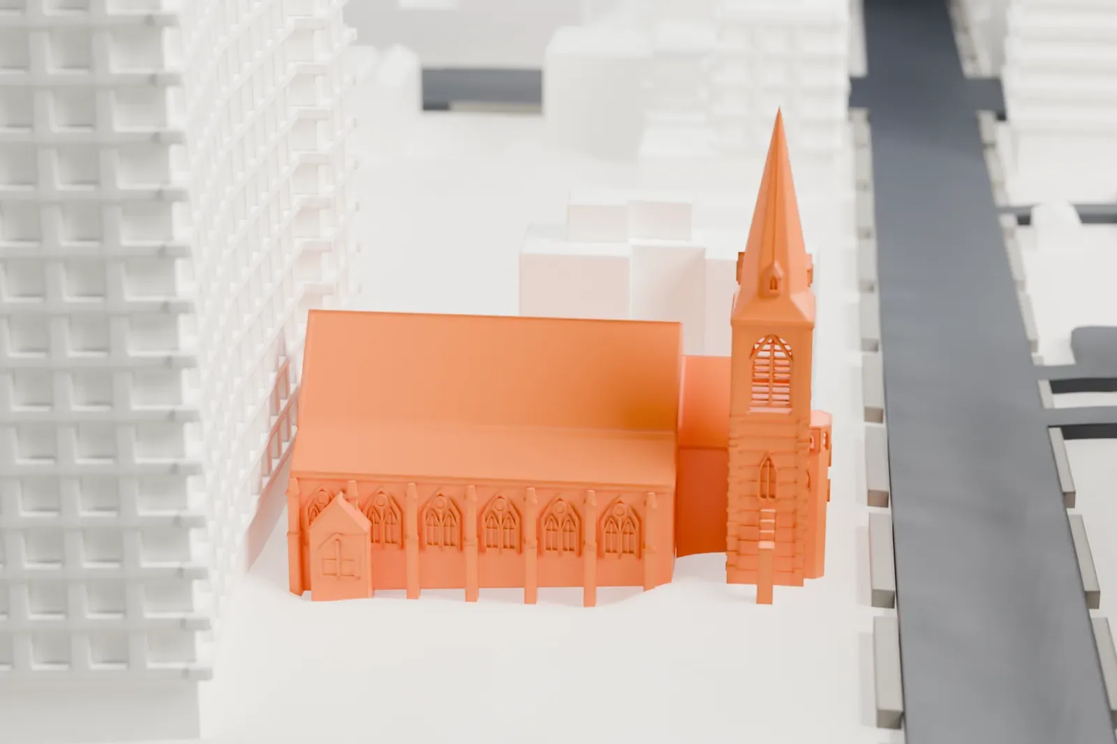 A white 3D print of St. Mary's Episcopal Church, a church with a tall spire and gabled roofs, among larger buildings and streets.