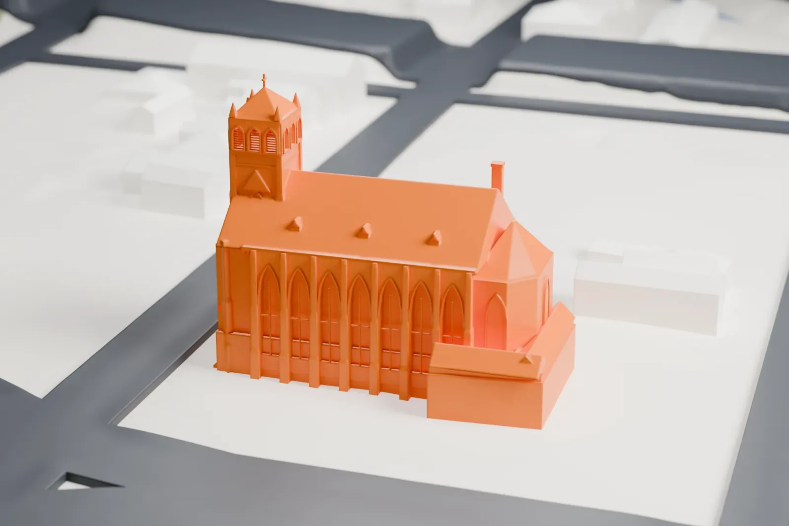 A white 3D print of St. Nicholas Church, a long church with a corner tower, tall pointed windows and a projecting apse, on its block beside streets and low buildings.