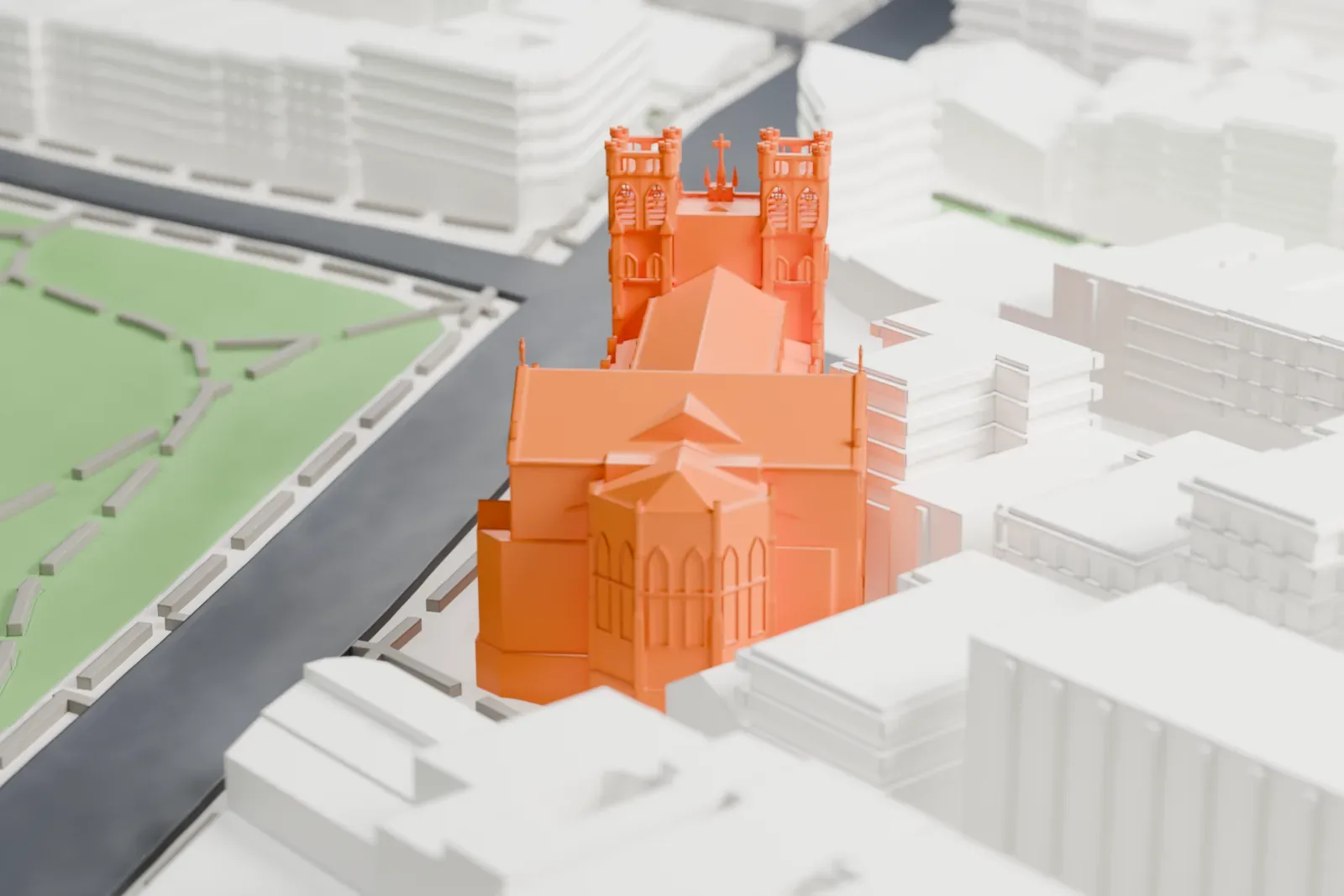 A white 3D print of St. Nicholas of Tolentine Church, a Gothic church with two crenellated towers and a long pitched roof, beside a street and a strip of park among larger buildings.