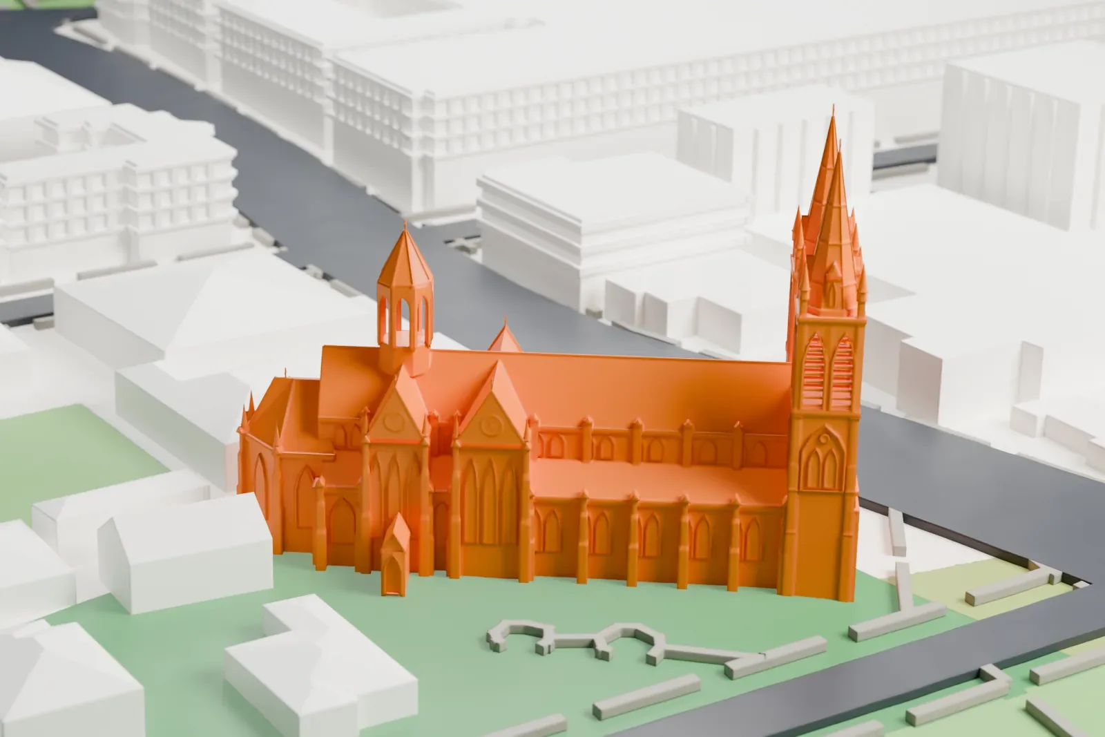 A white 3D print of St Peter's Cathedral, a Gothic church with two tall spired towers and steep roofs, standing on green lawns beside roads and low buildings.