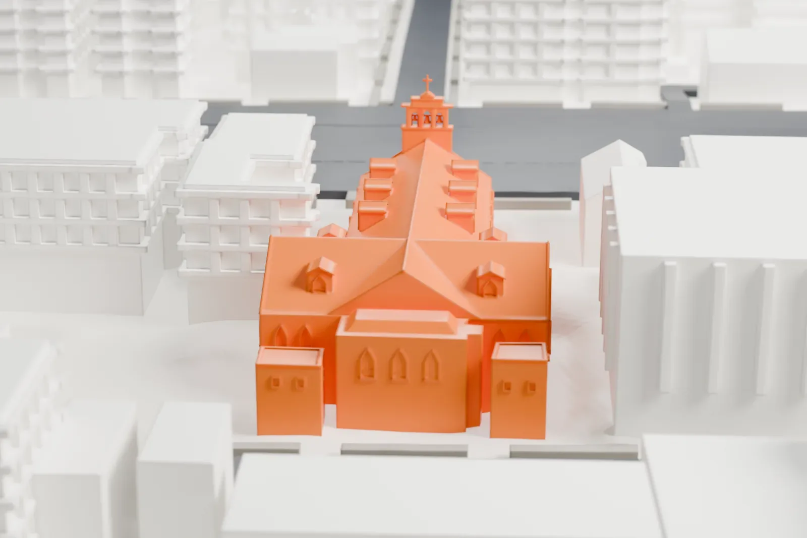 A white 3D print of St. Philip Neri's Church, a long stone church with steep roofs, small dormers and a bell tower with a cross, among surrounding buildings and streets.