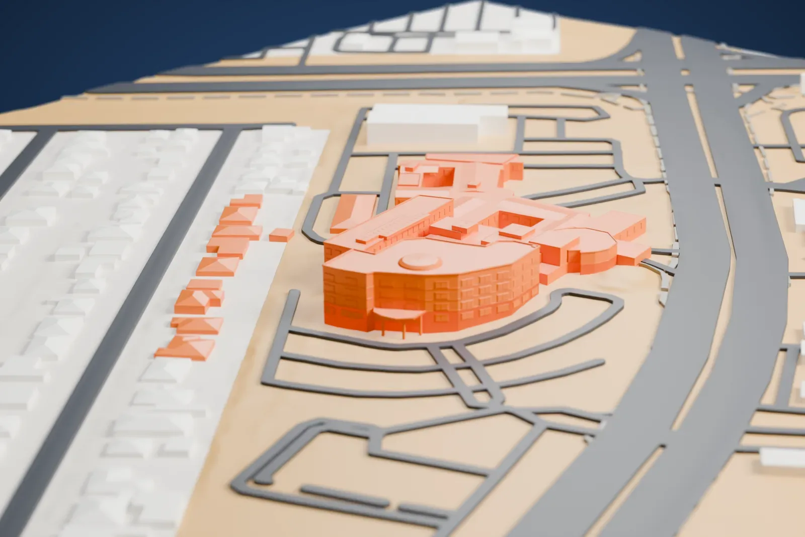 A white 3D print of the Rose de Lima Campus hospital, a group of joined wings with courtyards, beside a wide road and low neighborhood buildings.