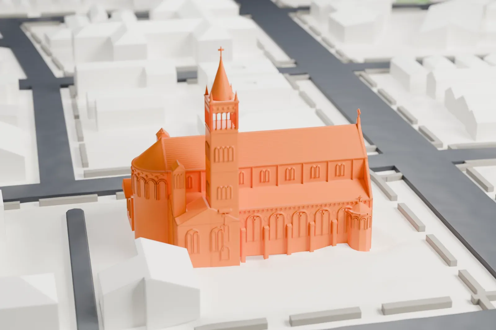 A white 3D print of St. Vincent de Paul Catholic Church, with its tall bell tower and rounded apse, standing on an open lot among low buildings and streets.