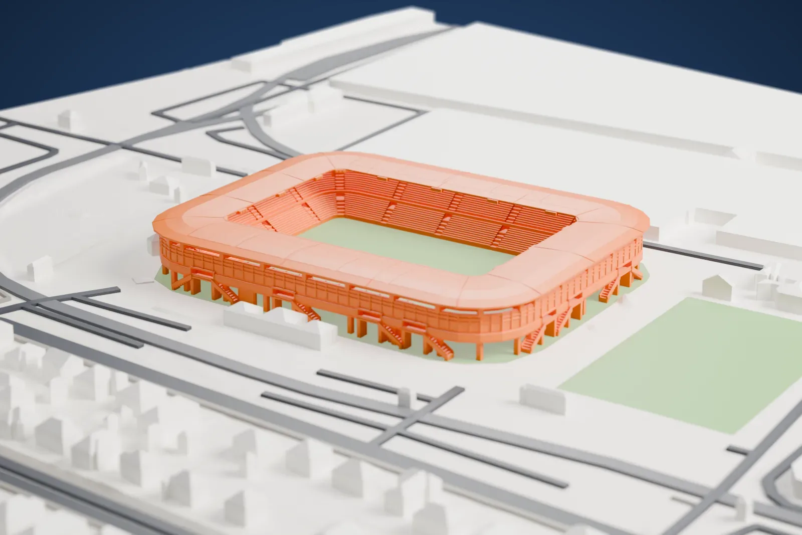 A white 3D print of Stade Auguste-Bonal, a roofed football stadium around a rectangular pitch, among the surrounding streets and buildings.