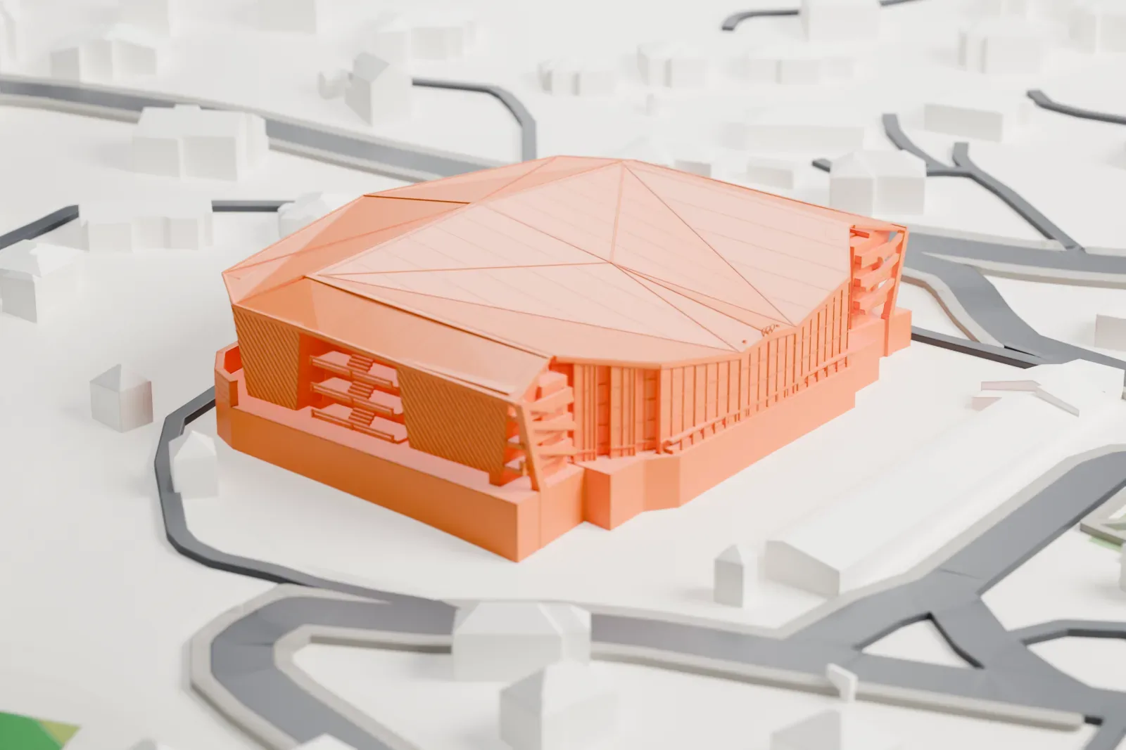 A white 3D print of Stadio Olimpico del Ghiaccio, a large arena under a faceted roof, among surrounding streets, houses and green areas.