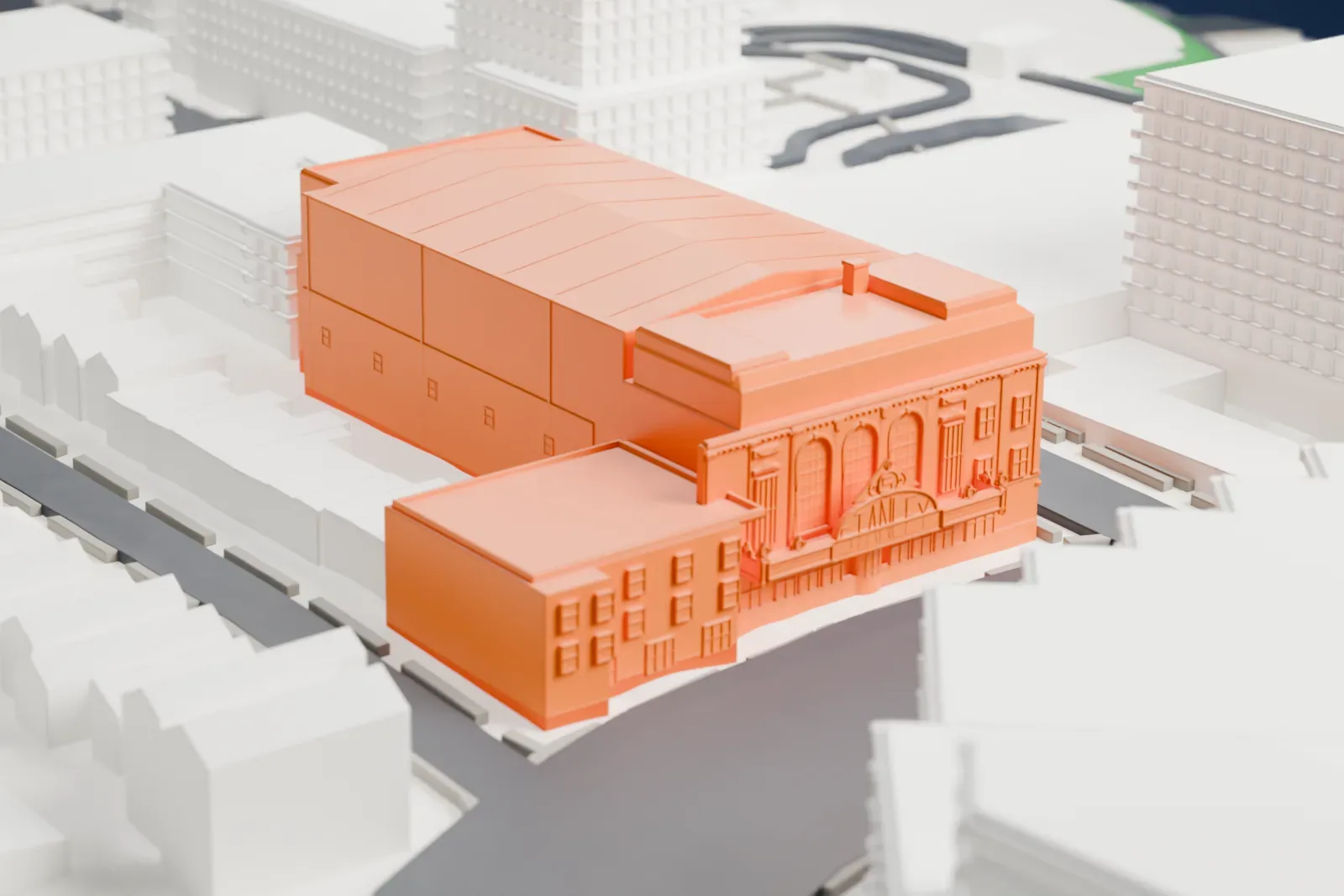 A white 3D print of the Stanley Theater, a large, long building with a ribbed roof, on a city block with smaller houses and taller buildings around it.