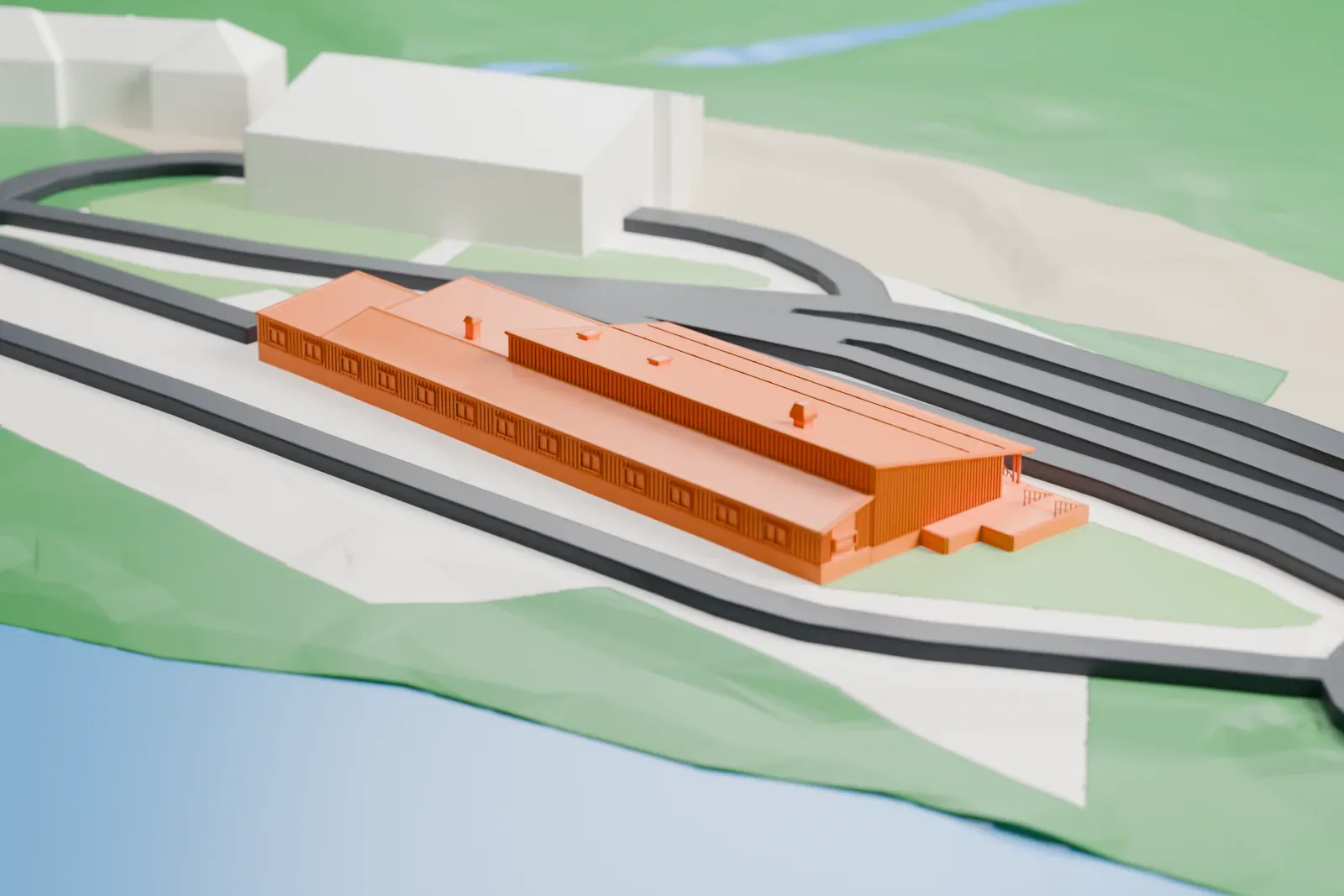 A white 3D print of the Storskog border station, a long low building with a pitched roof, beside curving road lanes, with slopes and water nearby.