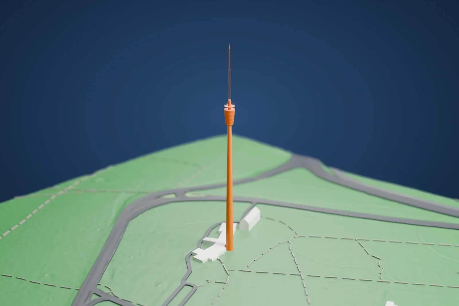 A white 3D print of Fernsehturm Stuttgart, a very slender tower with a round basket near the top and a thin antenna mast, standing on green parkland with a few low buildings at its base.