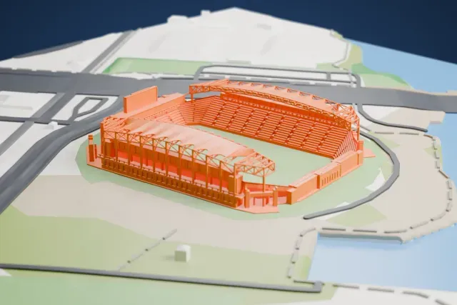 A white 3D print of Subaru Park, a soccer stadium with two roofed stands braced by lattice trusses, beside a river and a wide road.