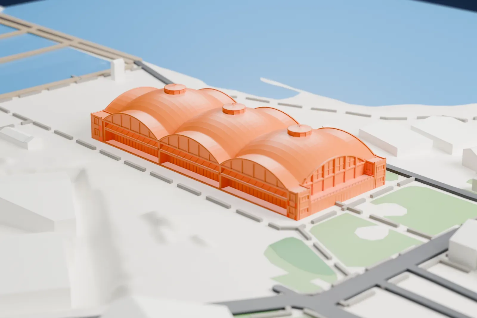 A white 3D print of the Seaplane Harbour hangars in Tallinn, three side-by-side barrel-vault halls, standing among low buildings, green patches and roads beside open water.