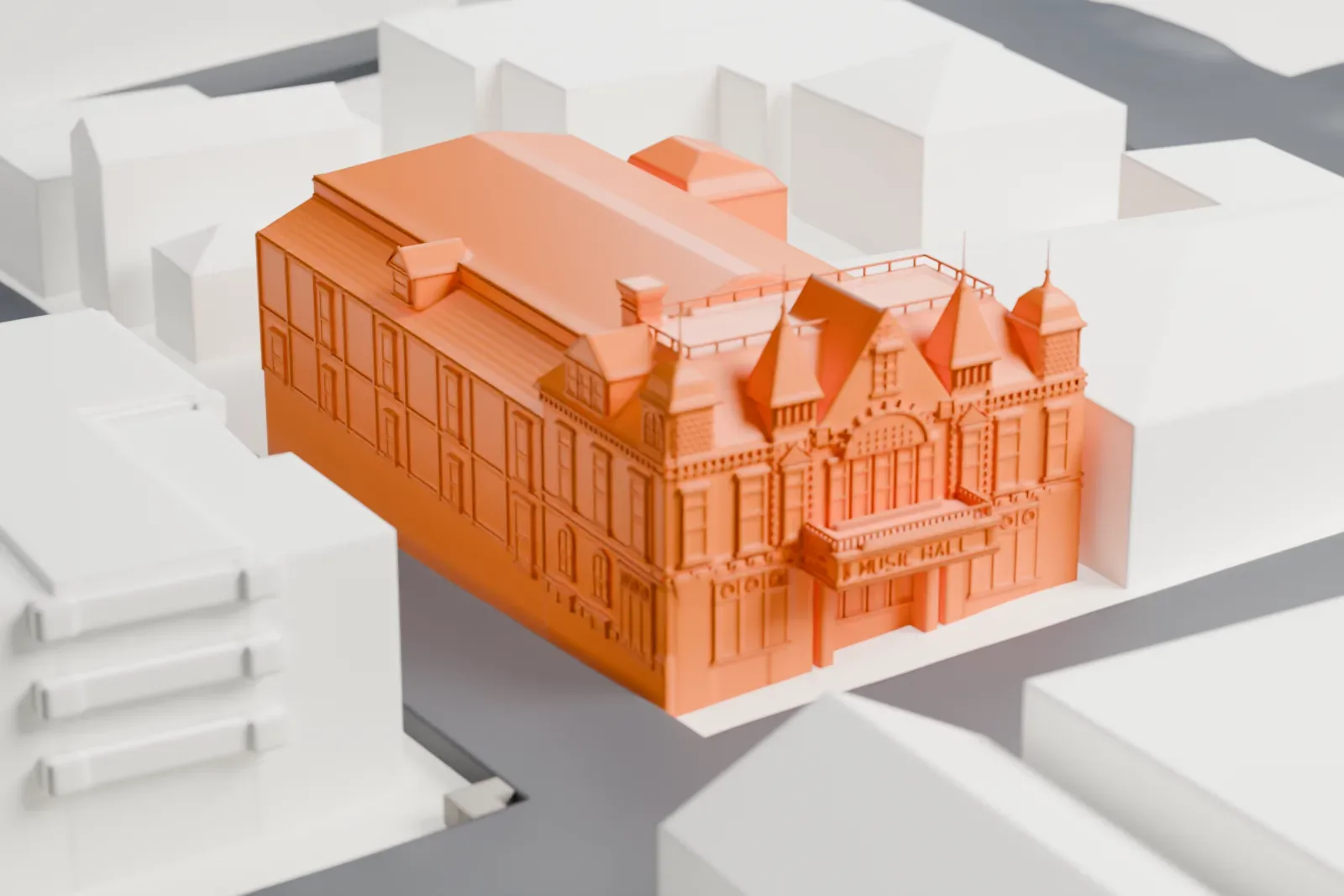 A white 3D print of the Tarrytown Music Hall, a long building with ornate corner towers and a large hipped roof, standing among low buildings and streets.