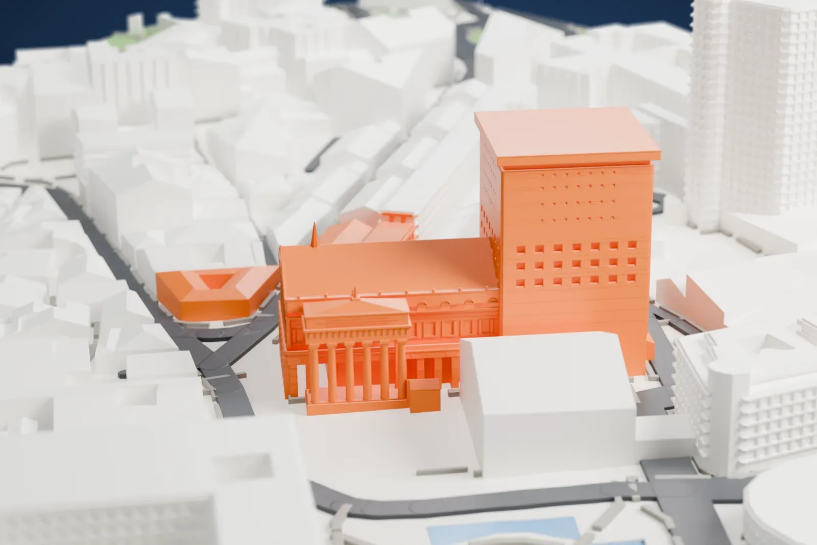 A white 3D print of the Teatro Carlo Felice, an opera house with a columned entrance portico, a pitched roof and a tall block behind it, among dense city buildings.