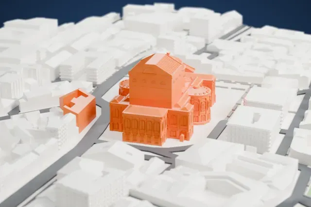A white 3D print of the Teatro Massimo, a domed opera house with a tall stage house, standing on a paved square among dense city blocks.