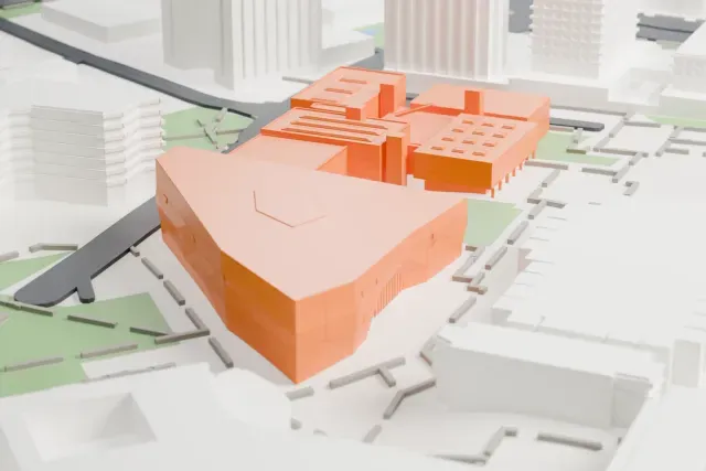 A white 3D print of the Tel Aviv Museum of Art, with an angular wing and low adjoining blocks among streets, taller buildings and open green space.