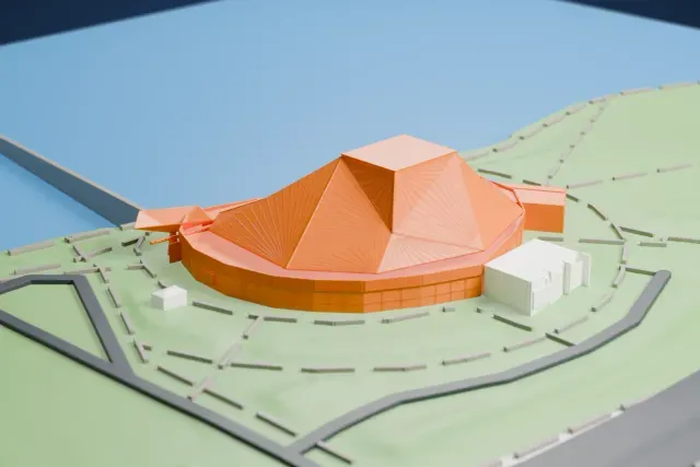 A white 3D print of Tempe Center for the Arts, a rounded building under a large folded, faceted roof, in a park beside a lake.