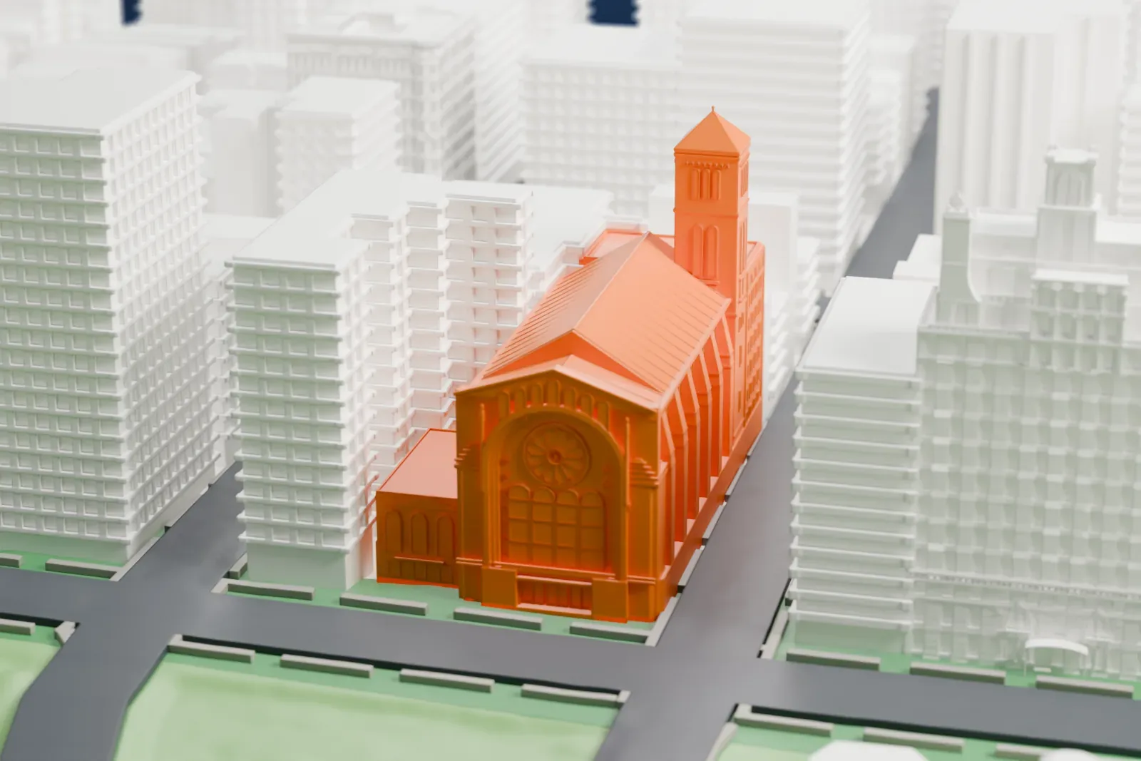 A white 3D print of Temple Emanu-El of New York, a large synagogue with a square tower and a round window on its front, among taller buildings with green lawns and streets nearby.
