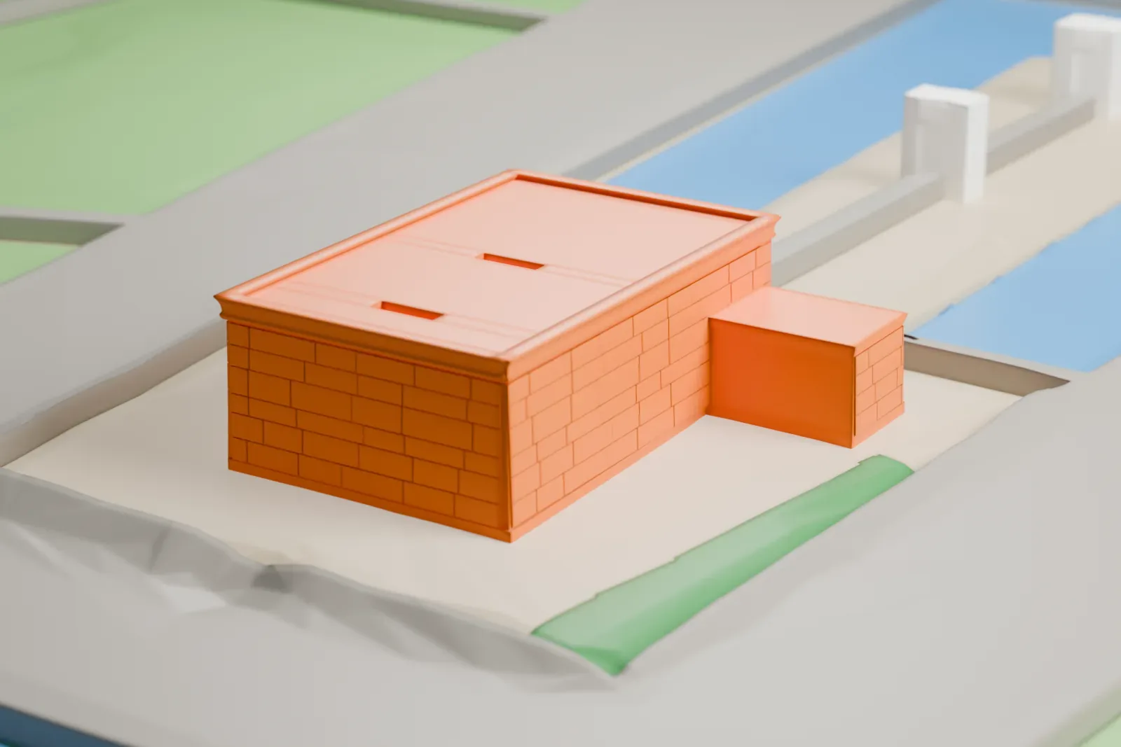 A white 3D print of the Temple of Debod, a low stone temple, standing in a park with city buildings beyond.