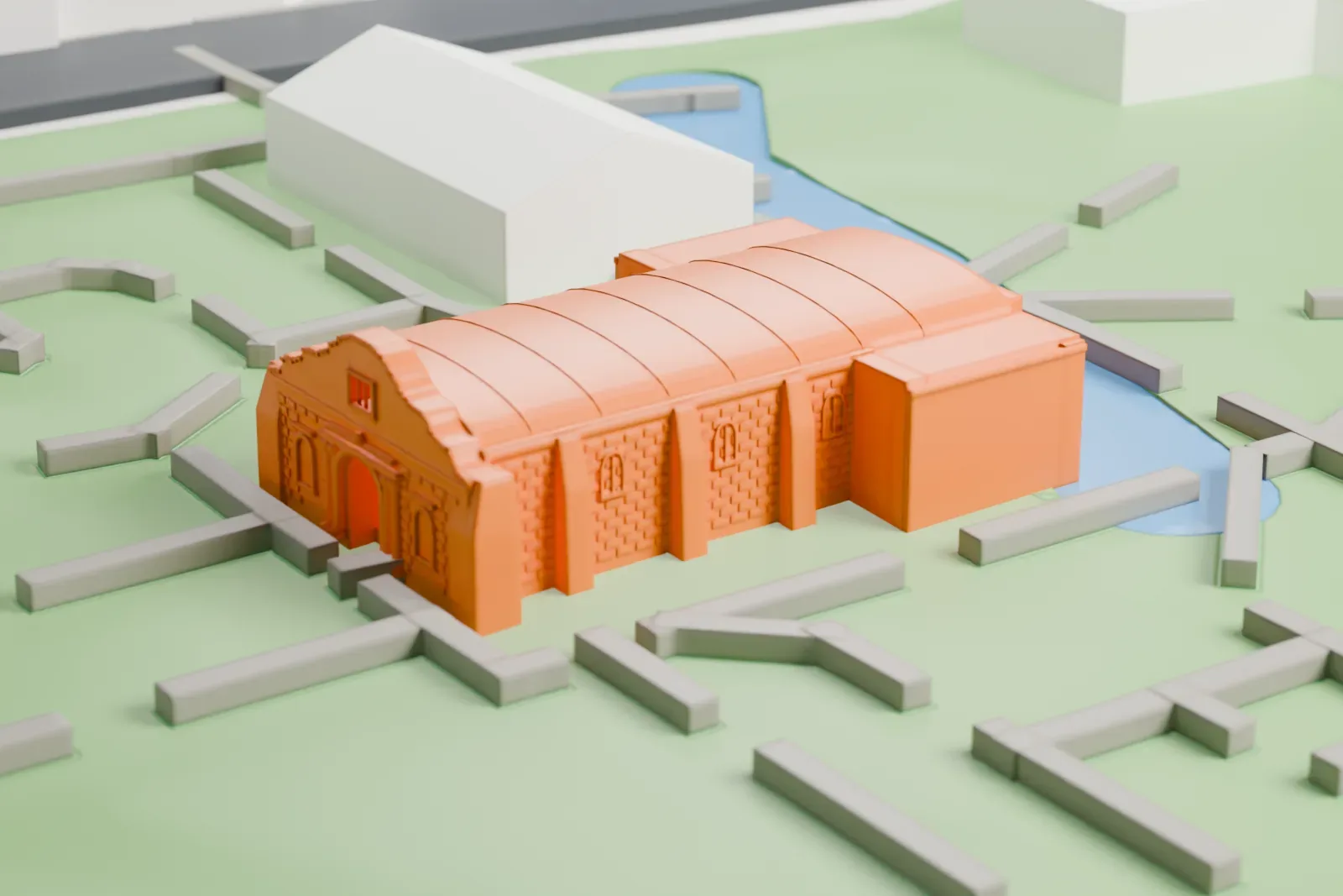 A white 3D print of the Alamo chapel, a low building with a curved barrel-vault roof and a carved front with columns and niches, on a green lawn with footpaths and a narrow stretch of water nearby.