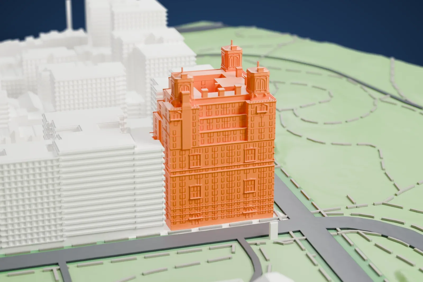 A white 3D print of The Beresford, a tall apartment building with three small octagonal towers and stepped terraces, beside a park and a road.