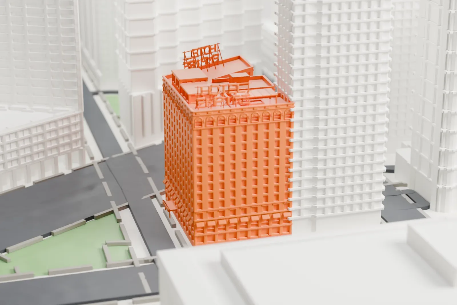 A white 3D print of The Empire Hotel, a tall corner building with a decorated roofline and rooftop structures, beside a street and a small green plaza.