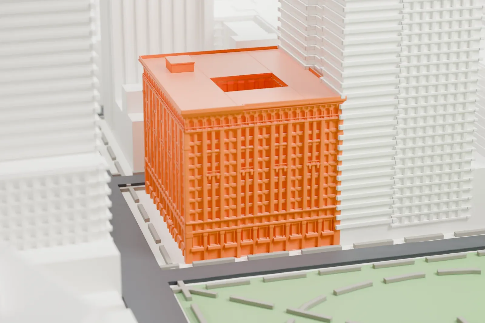 A white 3D print of The Grand Madison, a tall block with an ornate cornice and a recessed roof court, standing beside a green park and surrounded by taller buildings.
