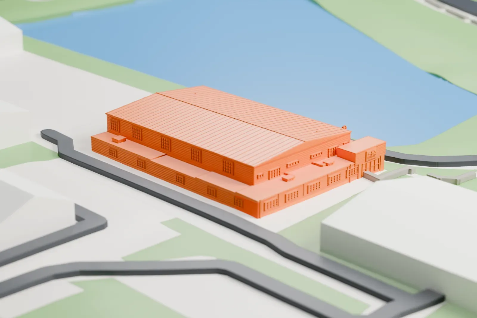 A white 3D print of The Hangar Flight Museum, a large gabled hangar with a ribbed roof, standing beside water with lawns, roads and other buildings around it.