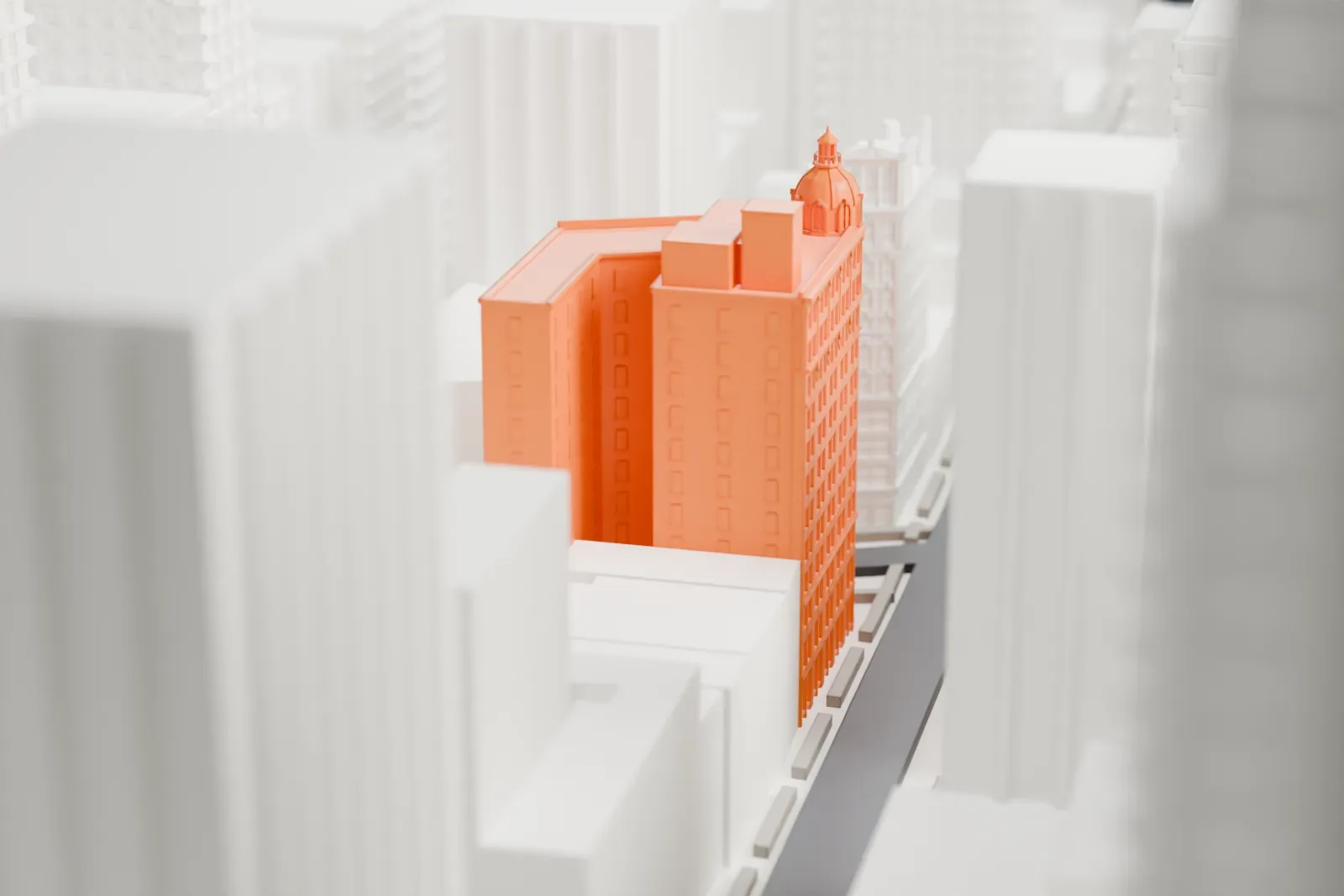 A white 3D print of The NoMad, a tall narrow building with a domed cupola on its corner, packed in among taller and shorter buildings.