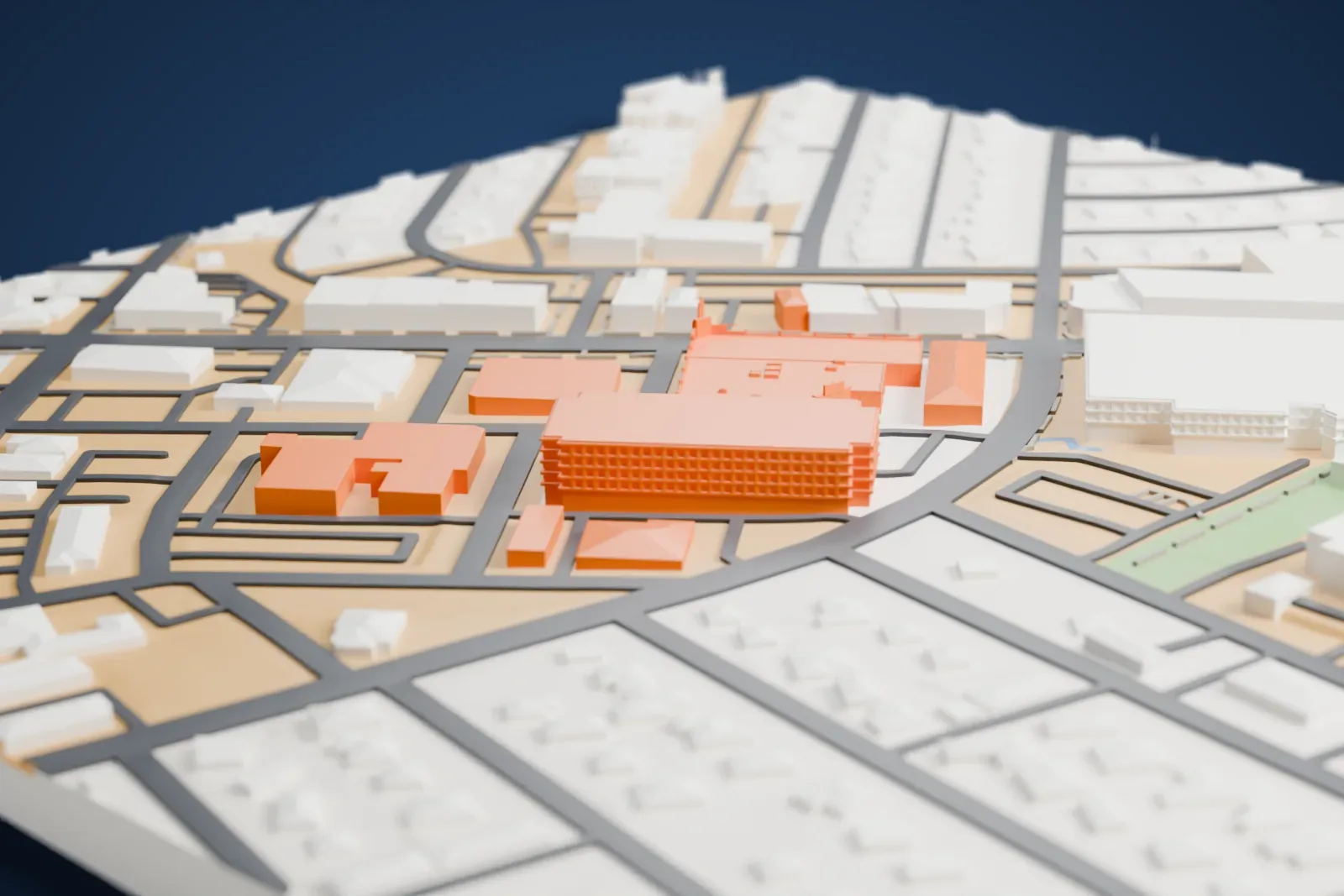 A white 3D print of The Pass Casino, a wide low building with a flat roof covered in small boxes, among streets, parking areas and taller gray buildings.