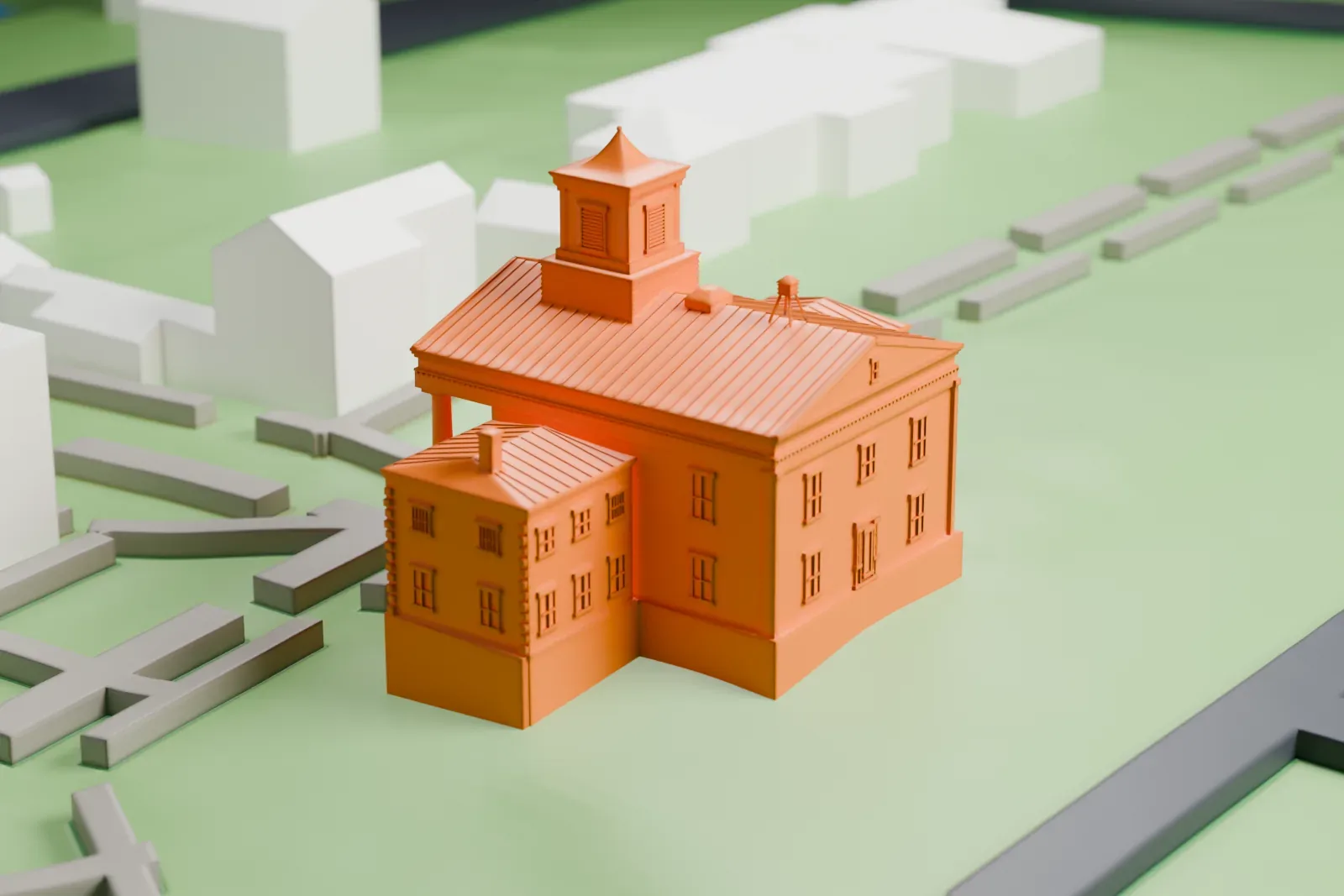 A white 3D print of the Third County Courthouse, a two-story building with a columned front and a cupola on its roof, on open lawn with streets and small buildings around it.