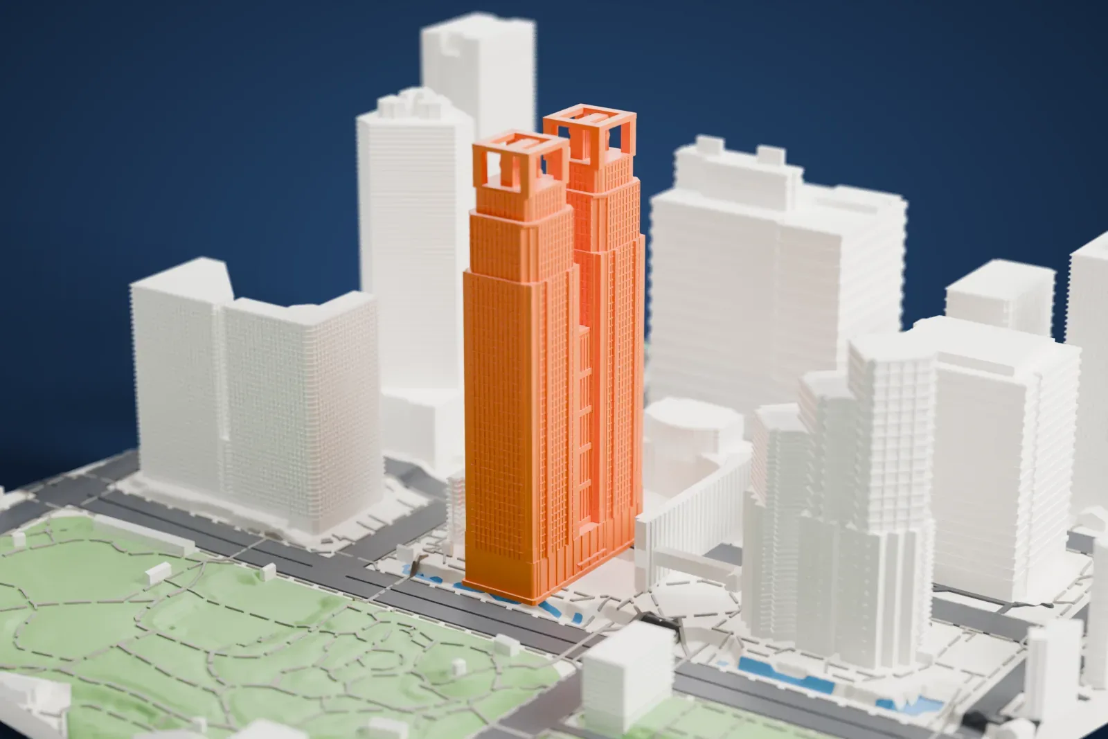 A white 3D print of Tokyo Metropolitan Government Building No. 1, a very tall building that splits into twin towers with open square frames at their tops, among tall neighboring buildings and a park with winding paths.