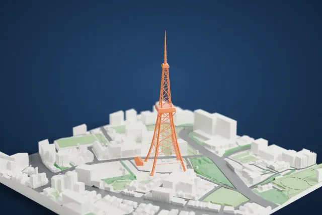 A white 3D print of Tokyo Tower, its open lattice frame rising above surrounding buildings, streets and green areas.