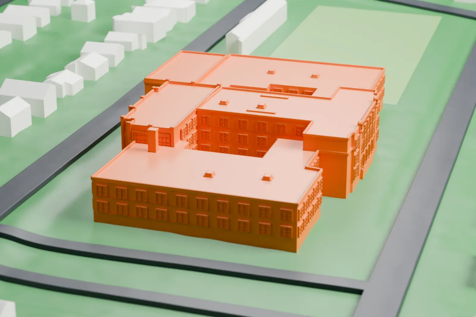 A white 3D print of Tuckahoe High School, a wide, low school building with several wings and flat roofs, with small houses around it and an open field alongside.