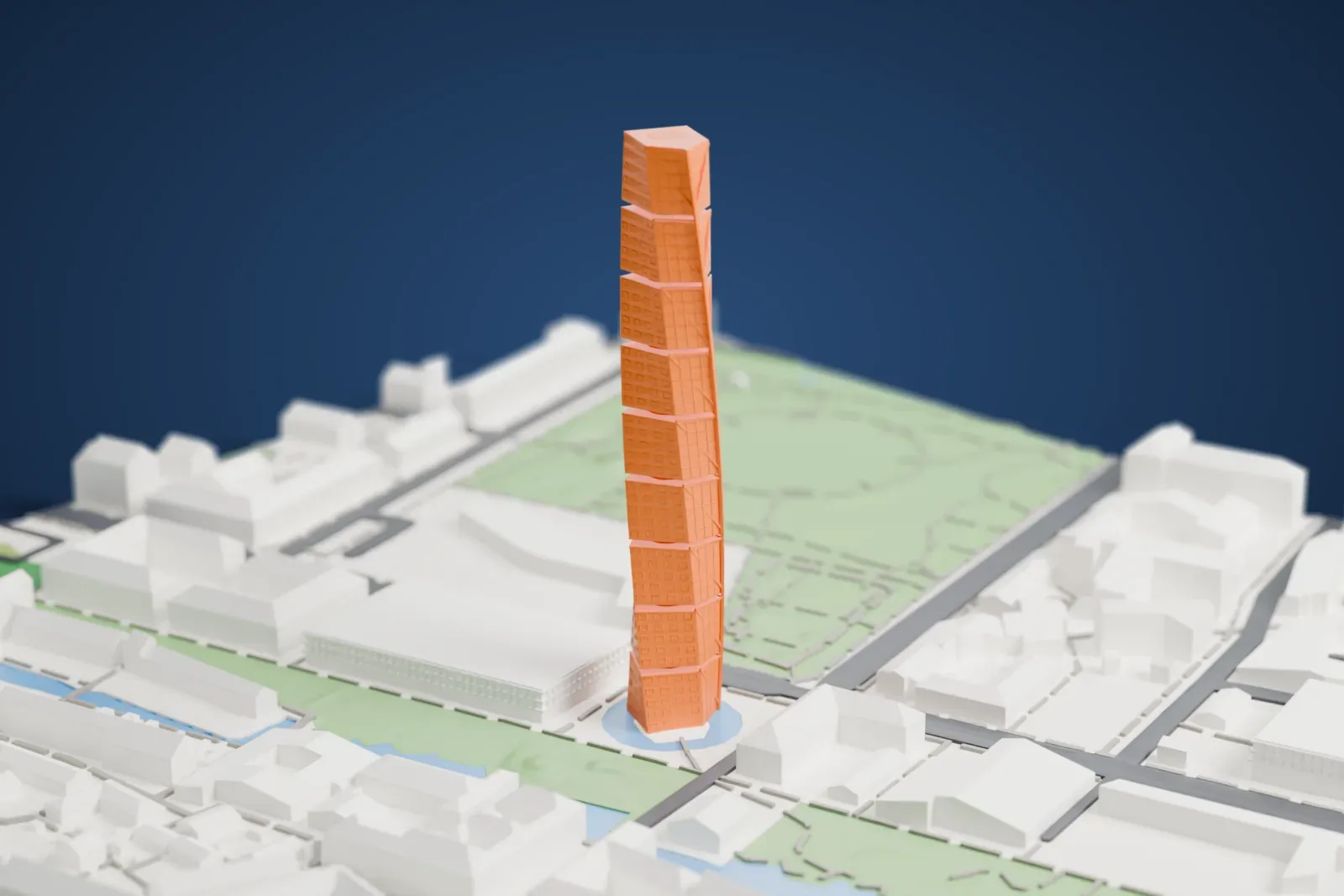 A white 3D print of the Turning Torso, a tall tower of stacked segments that twist as they rise, beside a strip of water with low buildings and green lawns around it.