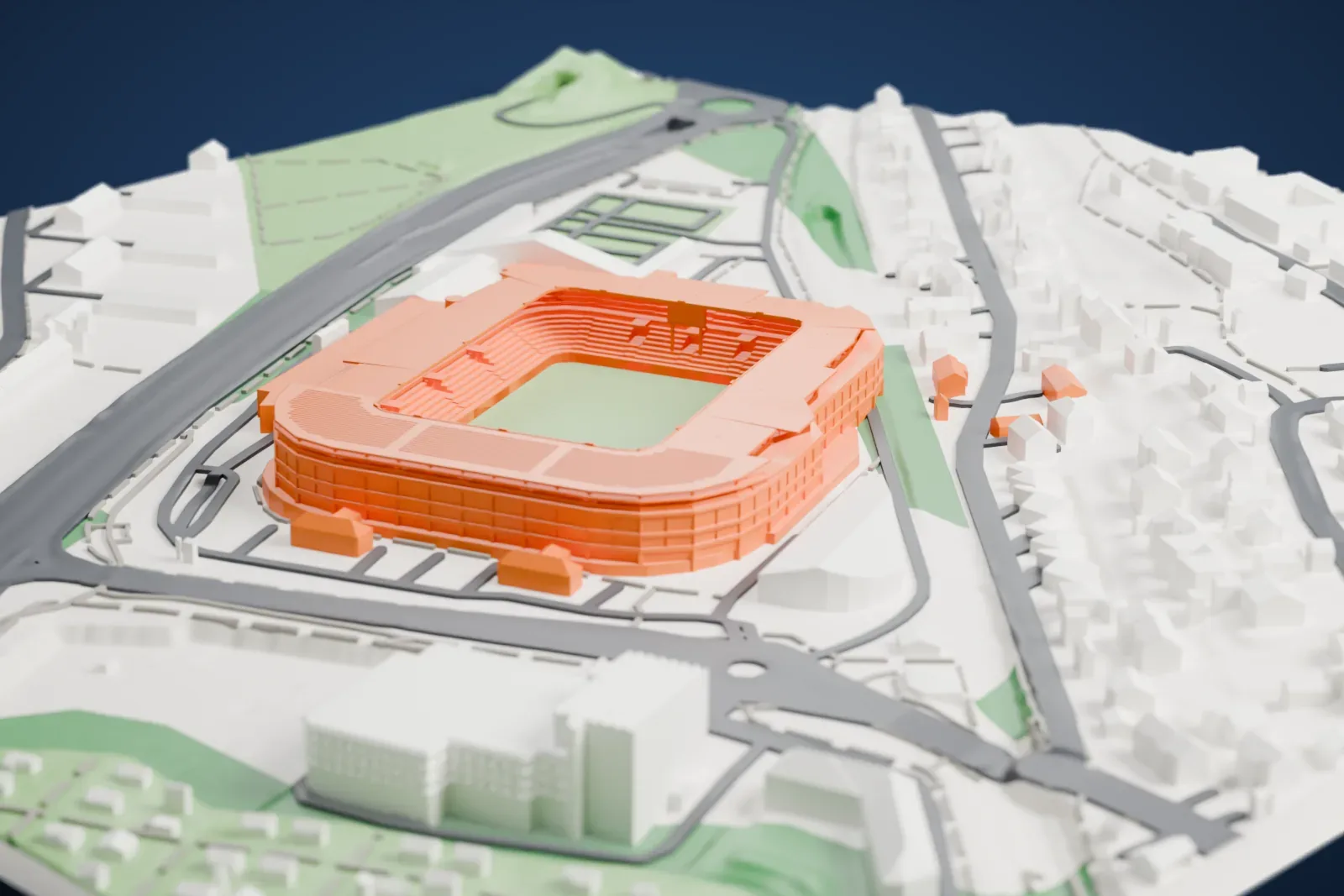 A white 3D print of Ullevaal Stadion, a compact rectangular football stadium with a roof ring around an open pitch, surrounded by roads, a few large buildings and low houses.
