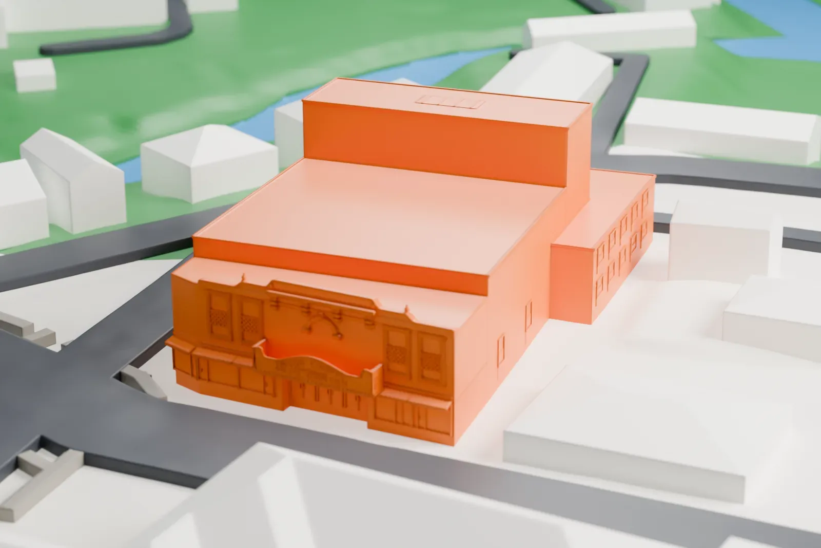 A white 3D print of Union County Performing Arts Center, a large block-shaped theater with a taller stage block, standing among small buildings, streets and green space.