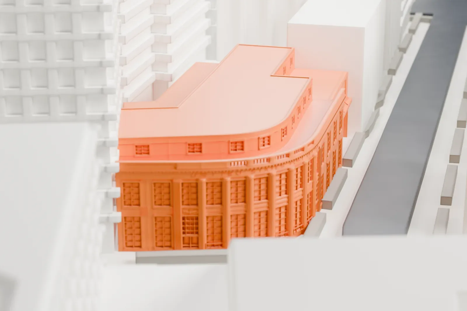 A white 3D print of the Cooper Station post office, a small low building, hemmed in by taller buildings and streets.